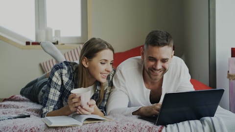 couple laying on bed on laptop